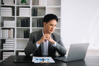 Ofiste elinde not defteri ve tabletle gülümseyen kendine güvenen Asyalı adam.