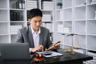 Adalet ve hukuk kavramı. Asyalı işadamı, avukat ya da muhasebeci akıllı telefon dizüstü bilgisayarı dijital tablet hesap makinesi ve bürodaki belgeleri kullanarak hesaplar üzerinde çalışıyor.