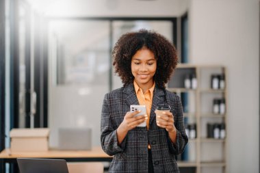Confident business expert attractive smiling young woman typing laptop ang holding digital tablet  on desk in creative office