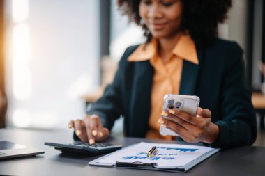 Güzel Asyalı kadın çalıştığı yerde bilgisayarını ve tabletini kullanıyor. Ofis işlerine odaklanmış..
