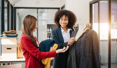 Boyunlarında santimetre boyayla çalışan ve tablet ve akıllı telefon tutan çeşitli kadın moda tasarımcıları. bağımsız yaratıcı tasarım işi.