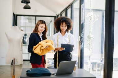 Boyunlarında santimetre boyayla çalışan ve tablet ve akıllı telefon tutan çeşitli kadın moda tasarımcıları. bağımsız yaratıcı tasarım işi. 