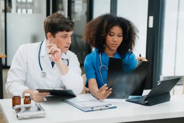 İki bilim adamı veya tıp teknisyeni, Asyalı kıdemli bir kadın bilim adamıyla çevrimiçi okuma, test örnekleri ve yeniliklerle laboratuarda buluşuyorlar.