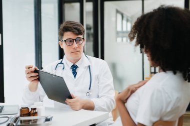 Hamile Afrikalı kadının klinikteki doktorla randevusu var. Stetoskop kullanan jinekolog erkek jinekolog kadın doğum uzmanı annesinin karnındaki bebeğin kalp atışlarını dinliyor. Hamilelik, sağlık konsepti