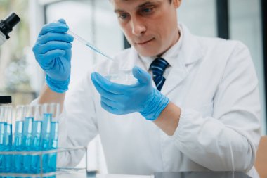 Olgun erkek bilim adamı bir laboratuarda deney yapıyor.