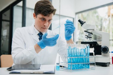 Olgun erkek bilim adamı bir laboratuarda deney yapıyor.