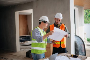 Mühendisler, büyük bir proje üzerinde yeni inşaat sahasında mimari projeyle veri çalışması ve dizüstü veya tablet üzerinde görüşüyorlar. Sabah...