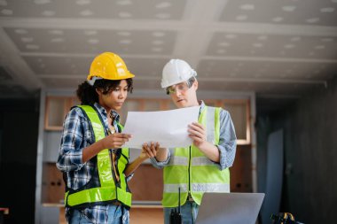 Mühendisler, büyük bir proje üzerinde yeni inşaat sahasında mimari projeyle veri çalışması ve dizüstü veya tablet üzerinde görüşüyorlar. Sabah...