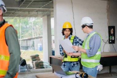Mühendisler, büyük bir proje üzerinde yeni inşaat sahasında mimari projeyle veri çalışması ve dizüstü veya tablet üzerinde görüşüyorlar. Sabah...