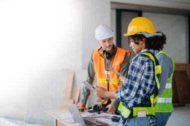 Mimar beyaz adam inşaat alanında meslektaşlarıyla karışık ırk üzerinde çalışıyor. Büyük projede mimarlık mühendisliği. İnşaat sürecinde bina içi.