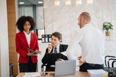 Genç iş adamları beyin fırtınası yapıyor. Yaratıcılık sektöründe oturup modern ofisteki işleri tartışıyorlar.
