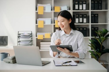 Tablet ve dizüstü bilgisayarda yazan genç ve güzel bir kadın. Çalışan ahşap masa, modern ofis.
