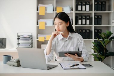 Tablet ve dizüstü bilgisayarda yazan genç ve güzel bir kadın. Çalışan ahşap masa, modern ofis.