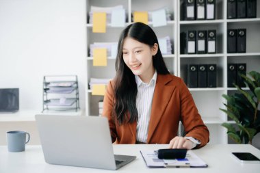 Tablet ve dizüstü bilgisayarda yazan genç ve güzel bir kadın. Çalışan ahşap masa, modern ofis.