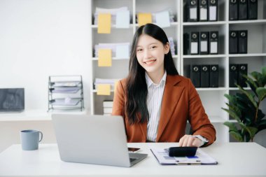 Tablet ve dizüstü bilgisayarda yazan genç ve güzel bir kadın. Çalışan ahşap masa, modern ofis.