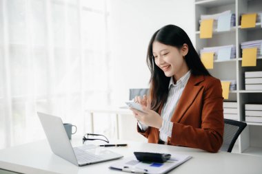 Tablet ve dizüstü bilgisayarda yazan genç ve güzel bir kadın. Çalışan ahşap masa, modern ofis.