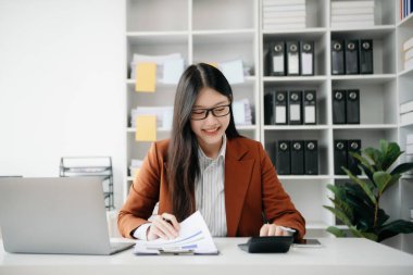 Tablet ve dizüstü bilgisayarda yazan genç ve güzel bir kadın. Çalışan ahşap masa, modern ofis.