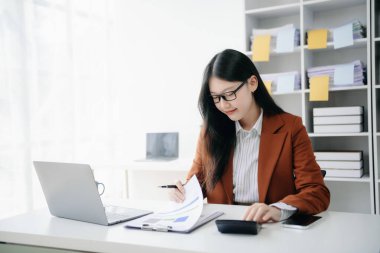 Tablet ve dizüstü bilgisayarda yazan genç ve güzel bir kadın. Çalışan ahşap masa, modern ofis.