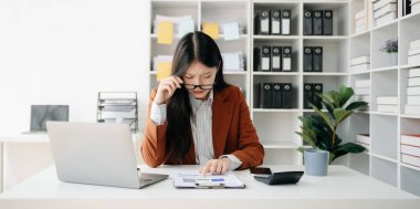 Woman who is tired and overthinking from working with tablet and laptop at office.