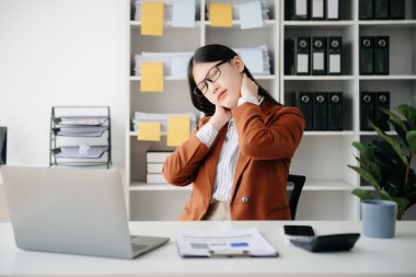 Ofis masasında uzun bir gün geçirdikten sonra boynu ağrıyan Asyalı genç işkadını ofis çalışanı. ofis sendromu kavramı