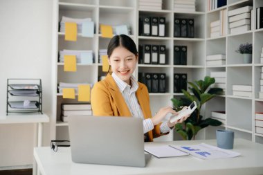 Ofiste elinde not defteri ve tabletle gülümseyen kendine güvenen Asyalı kadın.