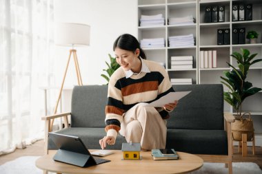 Ev modeli emlakçı ve müşteriyle birlikte çalışan Asyalı bir kadın ev, sigorta veya kredi emlak danışmanlığı için ev kredisi teklifiyle ilgili sözleşme üzerinde tartışıyorlar.