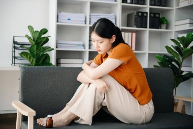 Asya 'lı genç bir kadın depresyonda oturuyor koyu saçlı dalgın bakışlar pencere kenarında duruyor ve anksiyete kopyalama alanı.