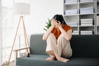 Asya 'lı genç bir kadın depresyonda oturuyor koyu saçlı dalgın bakışlar pencere kenarında duruyor ve anksiyete kopyalama alanı.