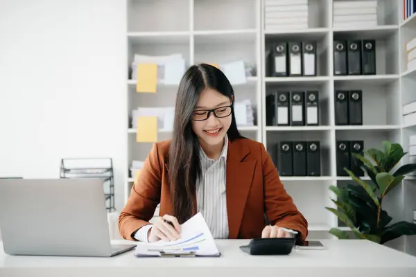 Tablet ve dizüstü bilgisayarda yazan genç ve güzel bir kadın. Çalışan ahşap masa, modern ofis.