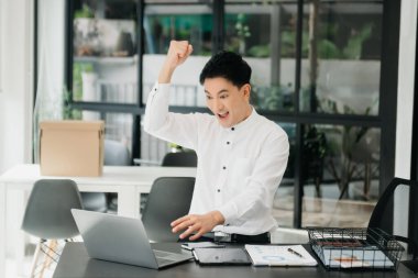 Tablet ve dizüstü bilgisayarda yazan yakışıklı genç adam ahşap masa modern ofisinde otururken.