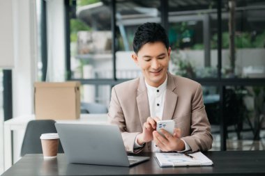 Tablet ve dizüstü bilgisayarda yazan yakışıklı genç adam ahşap masa modern ofisinde otururken.