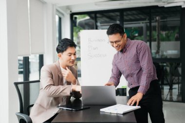 Ofisteki bilgisayarda çalışan iki genç iş arkadaşı birlikte bir proje üzerinde çalışıyorlar.