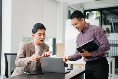 Ofisteki bilgisayarda çalışan iki genç iş arkadaşı birlikte bir proje üzerinde çalışıyorlar.