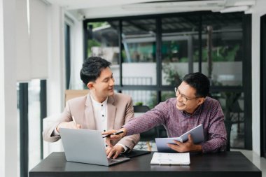 Ofisteki bilgisayarda çalışan iki genç iş arkadaşı birlikte bir proje üzerinde çalışıyorlar.