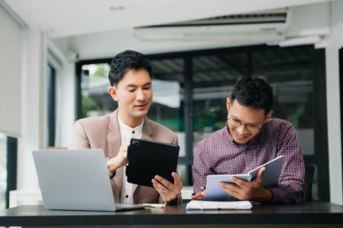 Ofisteki bilgisayarda çalışan iki genç iş arkadaşı birlikte bir proje üzerinde çalışıyorlar.