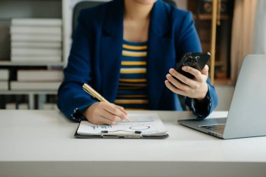 Ofiste bilgisayar, tablet ve akıllı telefon kullanan bir iş kadını. Dijital pazarlama medya mobil uygulaması ve yeni başlangıç planı tartışması. 