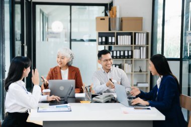 Bir grup Asyalı genç iş adamı iş planlarını tartışıyorlar yaratıcı iş dünyasında ofis inşaatını tartışıyorlar.