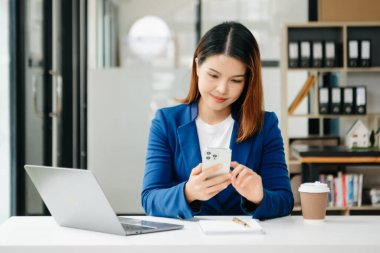 Kendine güvenen iş uzmanı, gülümseyen, dizüstü bilgisayarda yazan ve dijital tableti yaratıcı ofiste tutan çekici genç bir kadın..