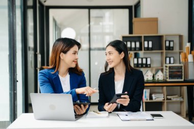 İş kadını takım toplantısını yönetiyor ve birlikte çalışma ofisinde mali durumuyla birlikte tablet ve dizüstü bilgisayar kullanıyor