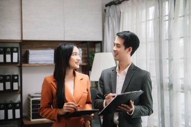 Asian business colleague business presents and explains and using laptop and tablet. Teamwork, financial marketing team,   while sitting in office room