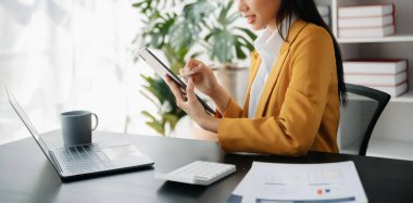 Ofiste bilgisayar, tablet ve akıllı telefon kullanan bir iş kadını. Dijital pazarlama medya mobil uygulaması ve yeni başlangıç planı tartışması.