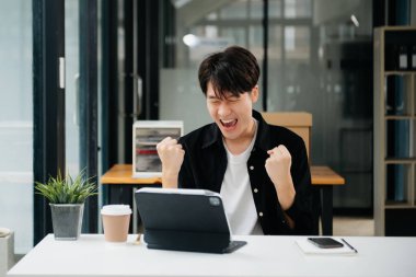 Asyalı iş adamları tablet, dizüstü bilgisayar üzerinde yaptıkları işlerden memnun ve mutlular.