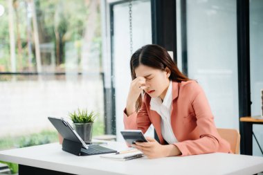 Hüsrana uğramış genç bir iş kadını bilgisayarla modern ofisindeki çalışma yerinde çalışıyor.