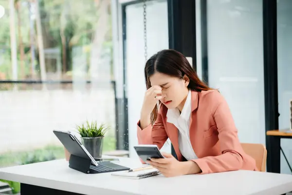Hüsrana uğramış genç bir iş kadını bilgisayarla modern ofisindeki çalışma yerinde çalışıyor.