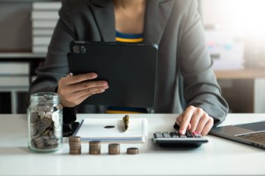 Bütçe kavramını hesaplamak için sürahi bardağa ve hesap makinesine madeni paralar koyarak tasarruf ediyoruz.