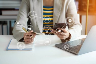 Mobil ödemeler için akıllı telefon kullanan bir kadın çevrimiçi alışveriş, Omni kanalı, masada oturan, sanal simge grafik arayüzü ekranı