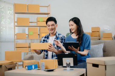 Başlangıçta küçük işletme KOBİ 'si, akıllı telefon ya da tablet kullanan girişimci sahibi erkek ve kadın ofiste online alışveriş siparişi alıp kontrol ediyorlar