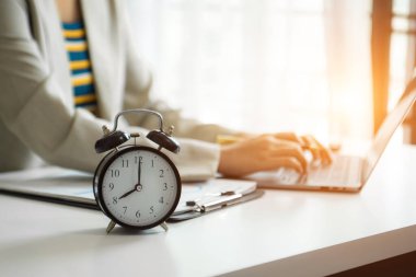 Masadaki çalar saat. Modern ofis binasında çalışan akıllı telefon, dizüstü bilgisayar ve tablet kullanan iş adamları 