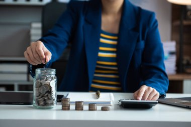 Bütçe kavramını hesaplamak için sürahi bardağa ve hesap makinesine madeni paralar koyarak tasarruf ediyoruz.