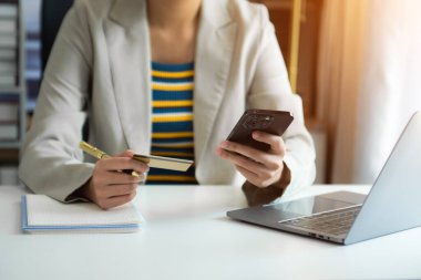 Mobil ödemeler için akıllı telefon kullanan bir kadın çevrimiçi alışveriş, Omni kanalı, masada oturan, sanal simge grafik arayüzü ekranı